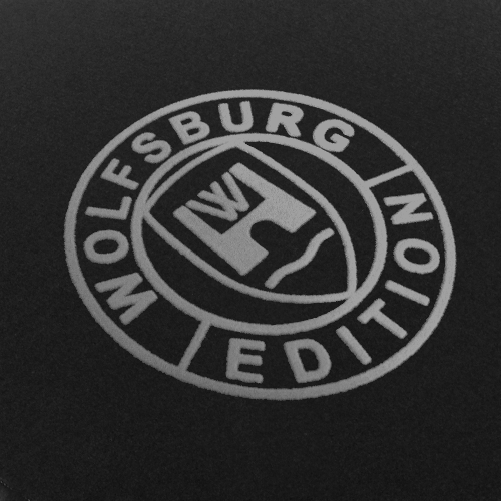 Das Wolfsburg Editions Logo auf einem schwarzen Teppich und das Logo ist in silbergrau.