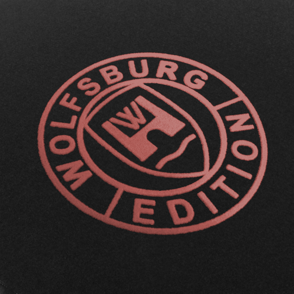 Das Wolfsburg Editions Logo auf einem schwarzen Teppich und das Logo ist in rose.